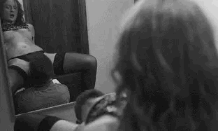 A woman watches herself in the mirror as a man gives her oral sex Gif.