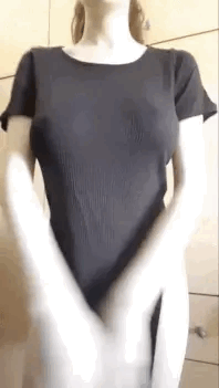 A woman wearing a black dress strips naked revealing her huge boobs.