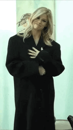 A gorgeous blonde woman opens up her long coat to reveal her naked body.