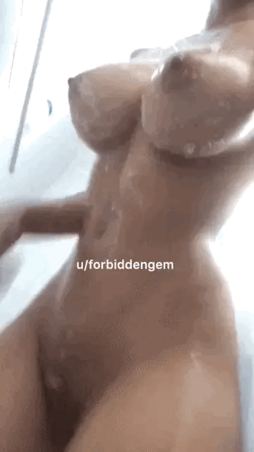 A woman woman with big pert boobs and a shaved pussy in the shower.