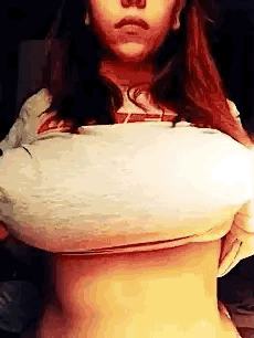 A teen brunette girl lifts her T-shirt to flash her massive big boobs.