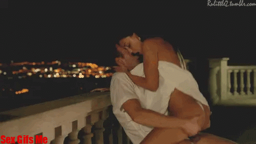 A couple enjoy having sex on their balcony at night time.